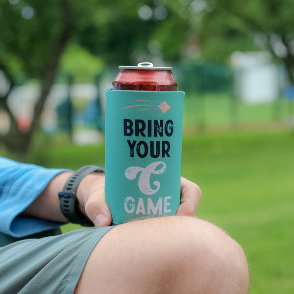 Lifestyle photo of person holding can with coolie that reads "Bring Your C Game".